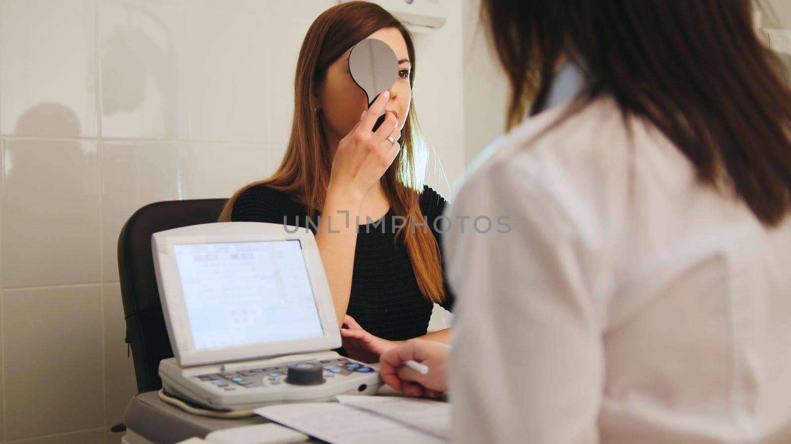 Ophthalmology - white woman checks vision in an ophthalmologist room - short-sighted and squints, telephoto