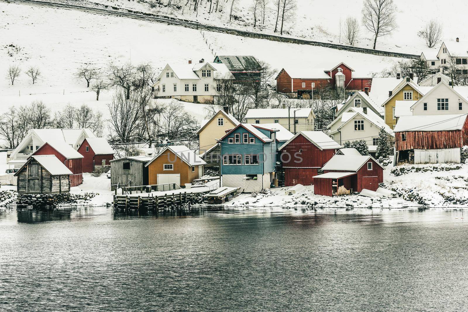 wooden houses on the banks of the Norwegian fjord, beautiful mountain landscape in winter