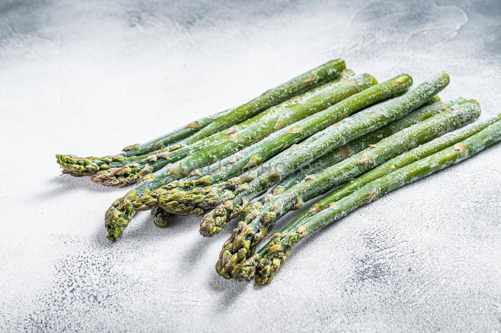 Frozen cold asparagus on a old kitchen table. White background. Top view by Composter