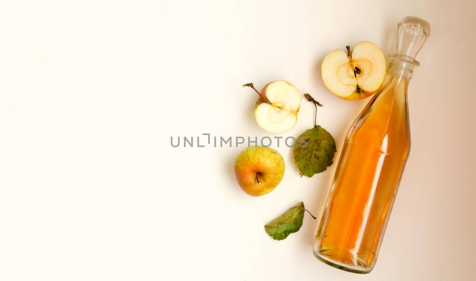 A bottle of apple cider vinegar and apple fruit composition with leaves on white background. copyspace.