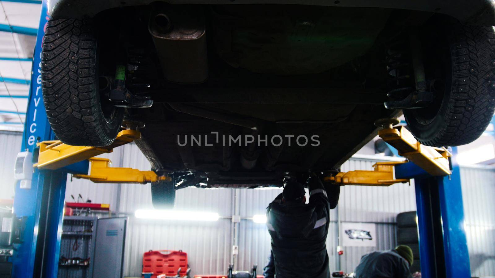 Automobile service - mechanic wrapping working device under car bottom, wide angle