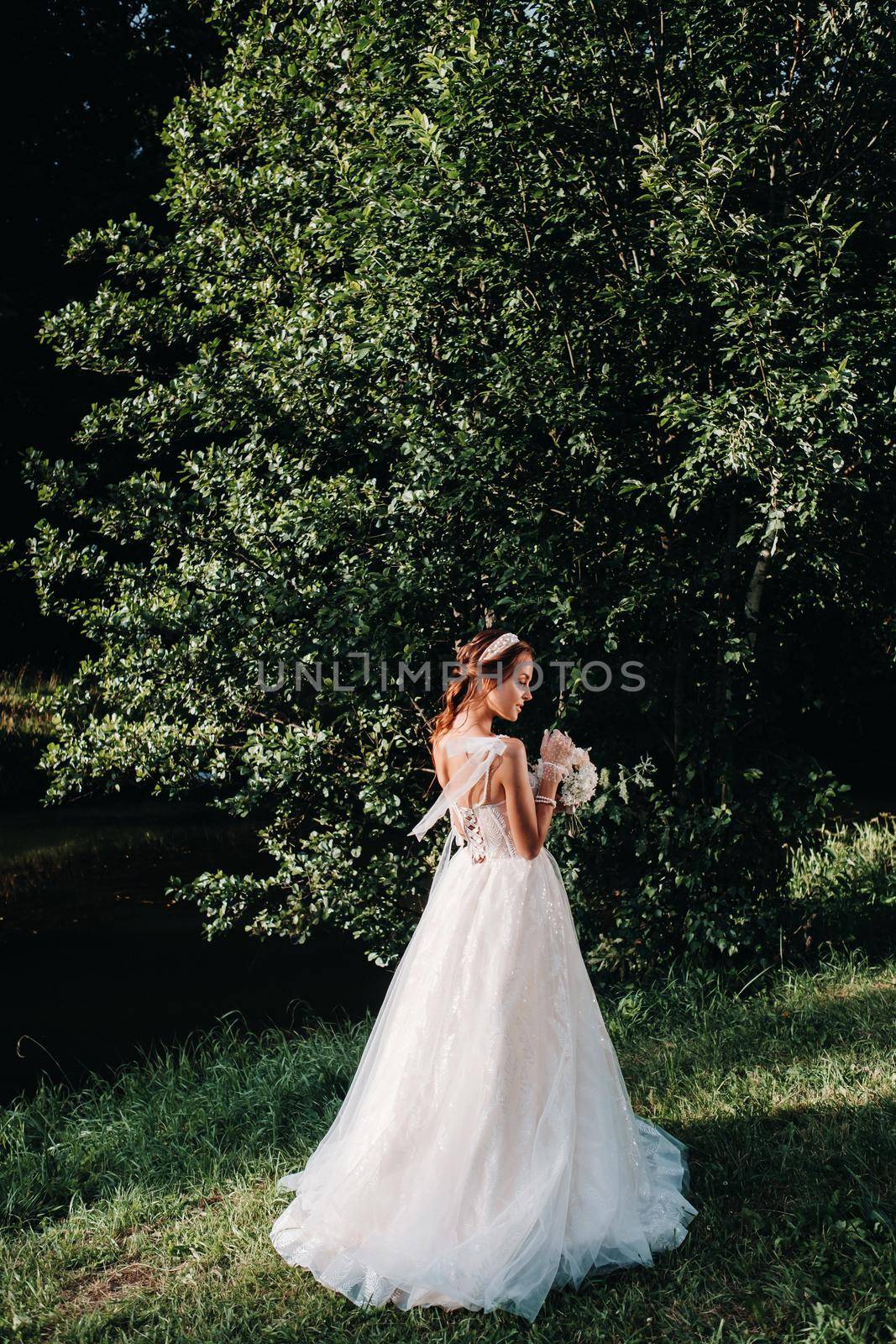 portrait of an elegant bride in a white dress with a bouquet in nature in a nature Park.Model in a wedding dress and gloves and with a bouquet .Belarus by Lobachad