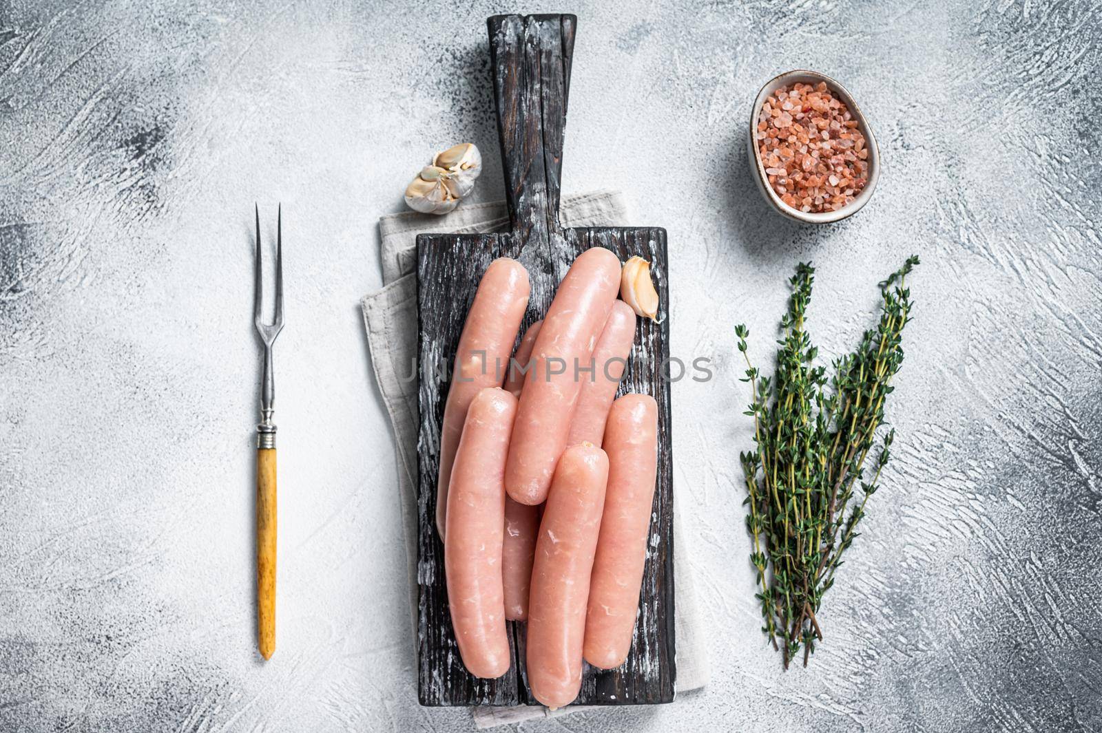 Chicken and turkey meat raw sausages on a wooden board with thyme. White background. Top view by Composter