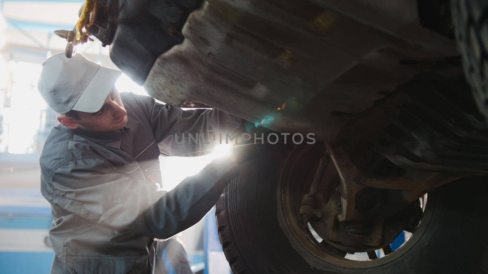 Garage automobile service - a mechanic working the wheel, bcklight, horizontal