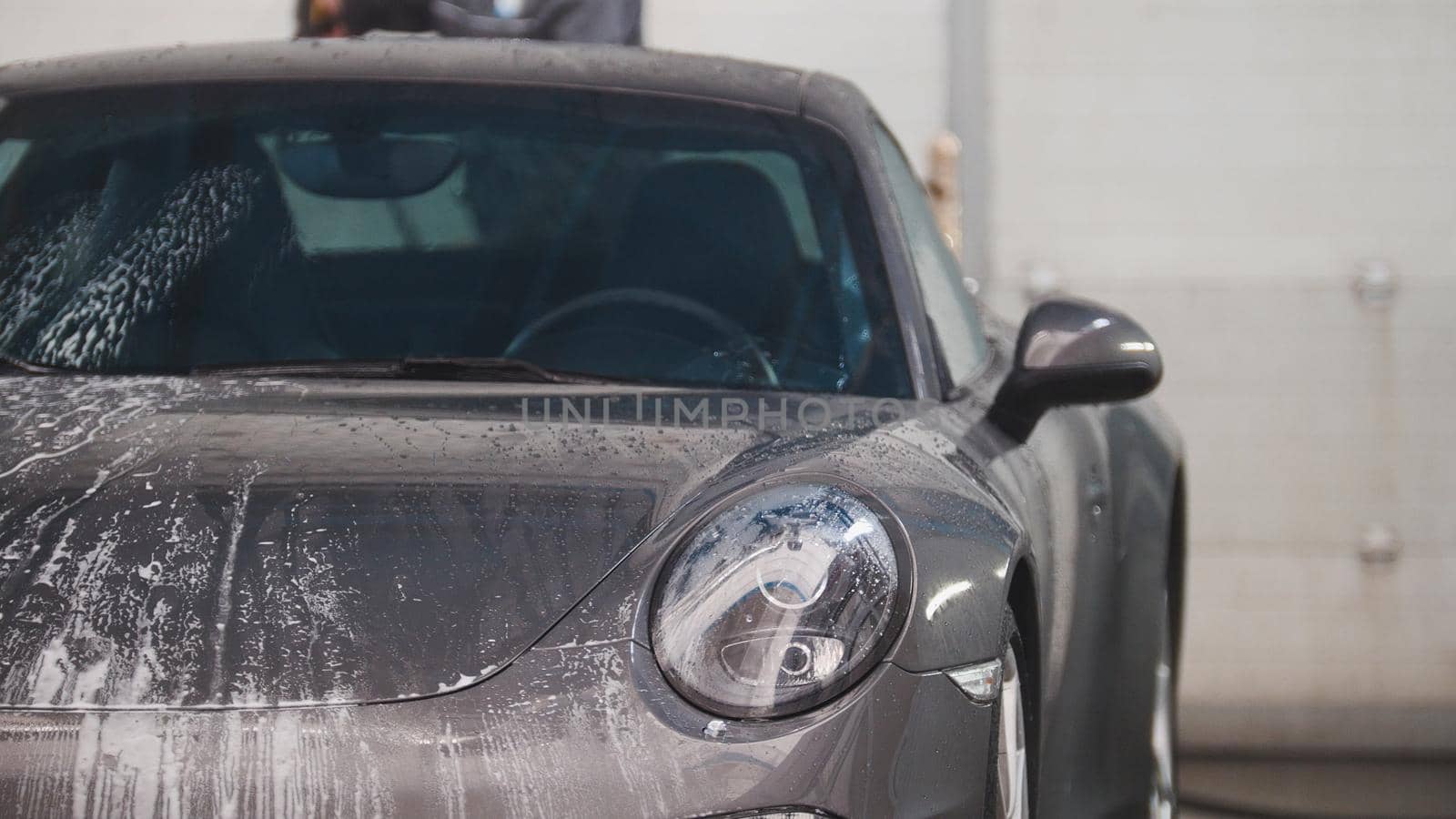Washing automobile - sportcar in the suds by water hoses, telephoto