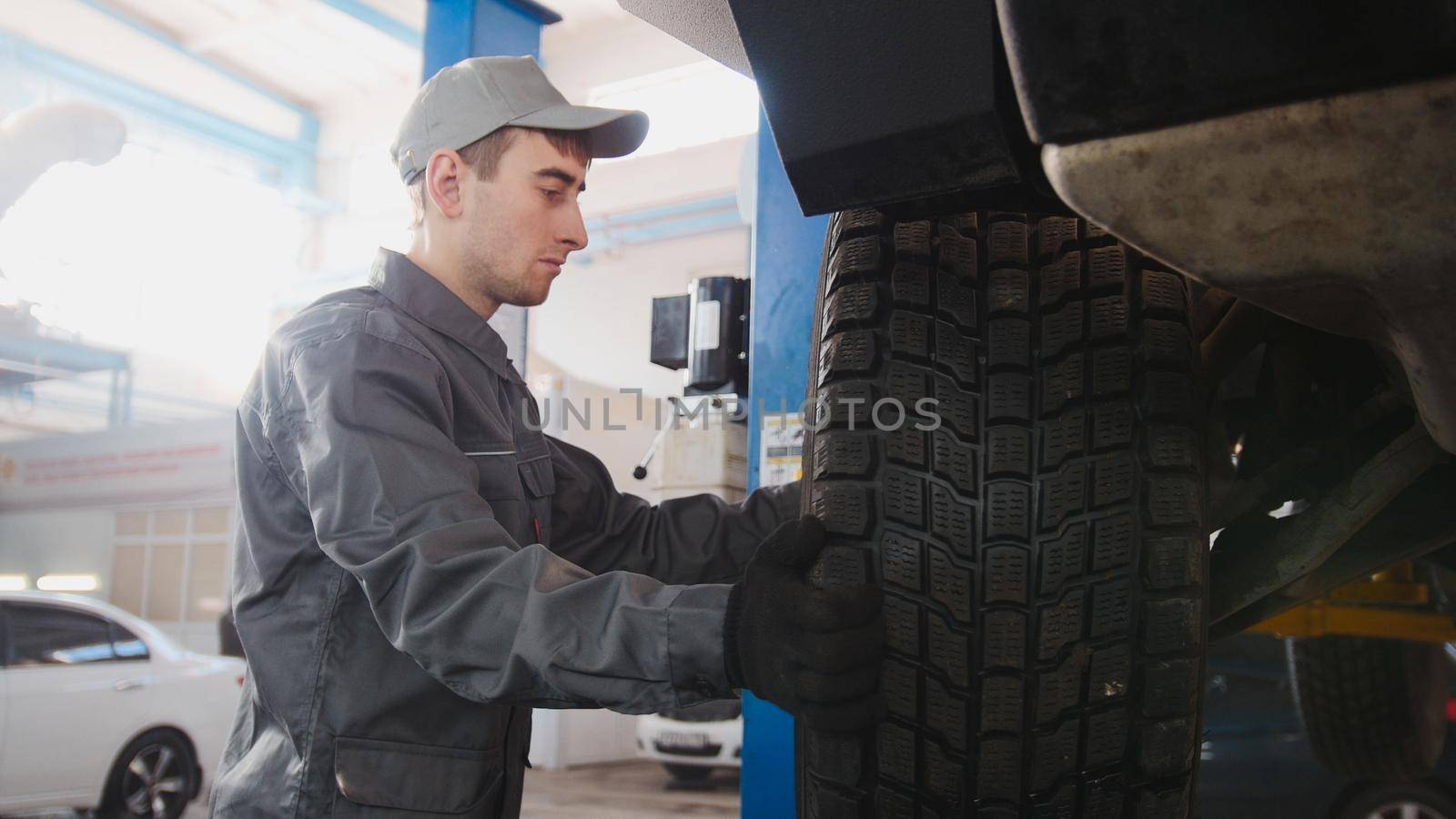 Garage automobile service - a mechanic working the wheel, close up, horizontal