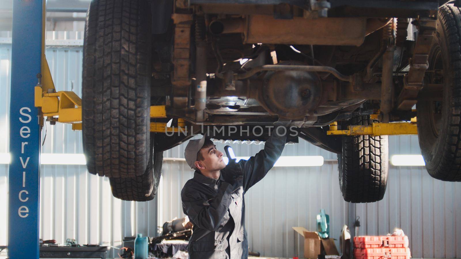 Car service - a mechanic checks the suspension of SUV, wide angle, horizontal