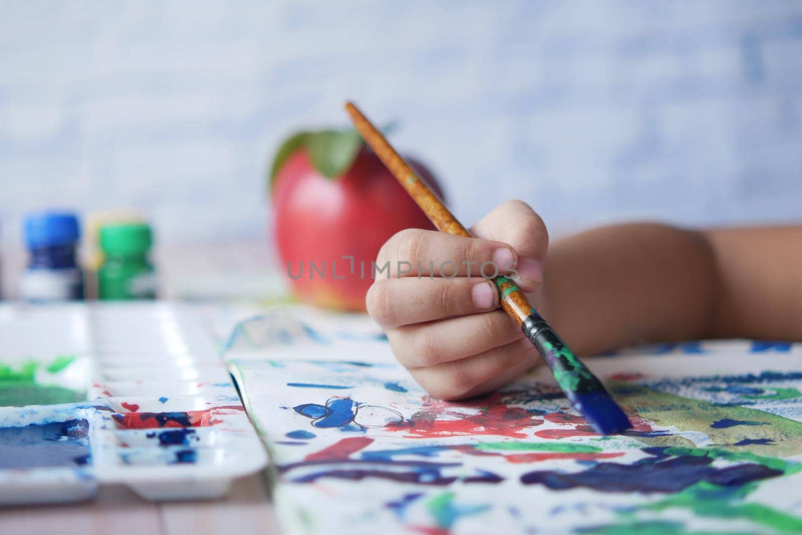 child girl drawing on paper with art brush .