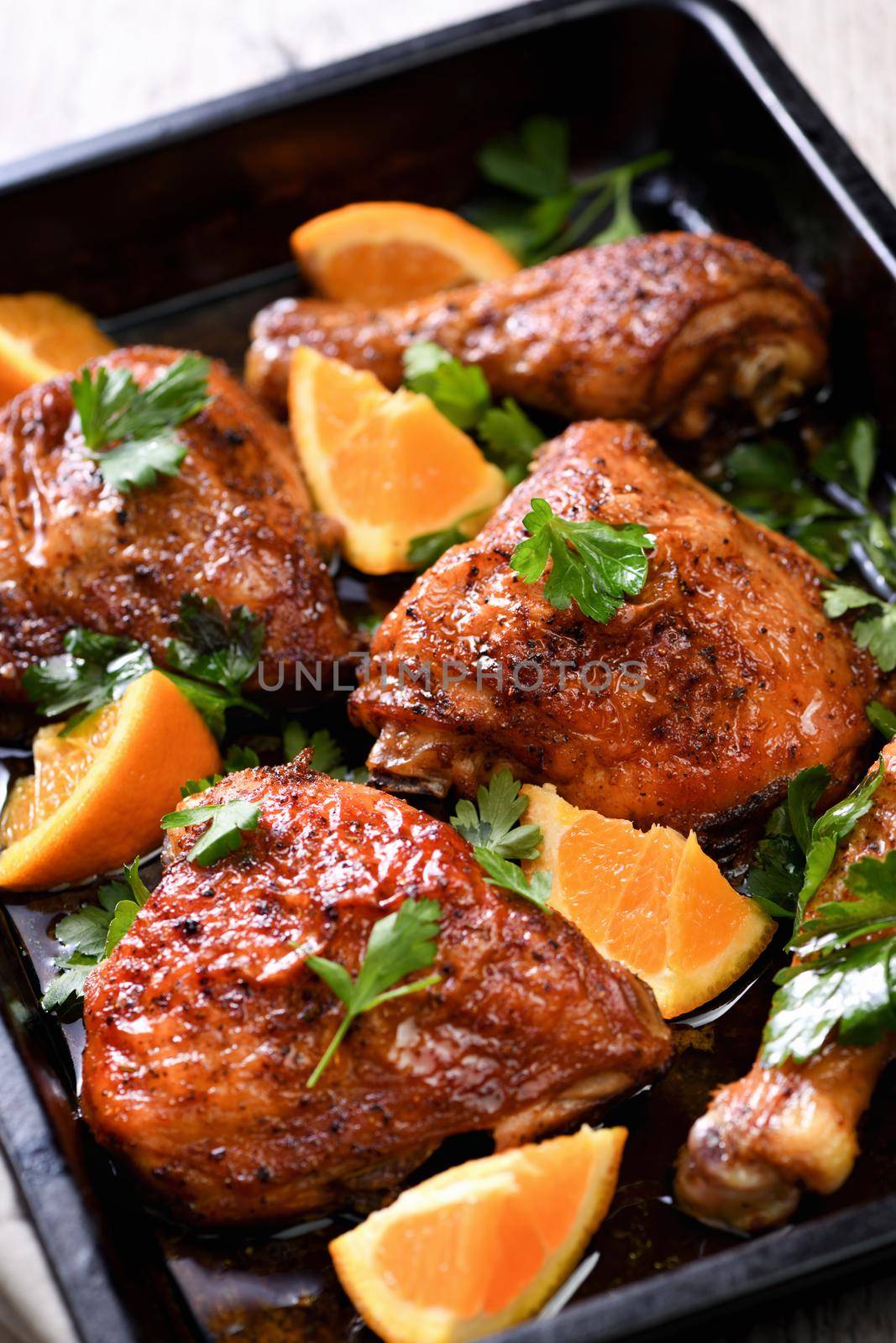 appetizing slices of baked chicken with crispy fried crust and oranges in a baking sheet