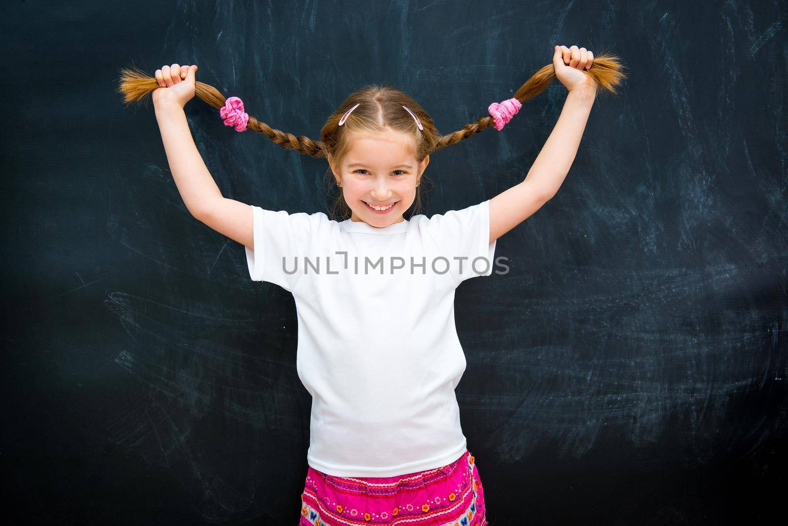 cute little girl in a white shirt against the school board raised pigtails