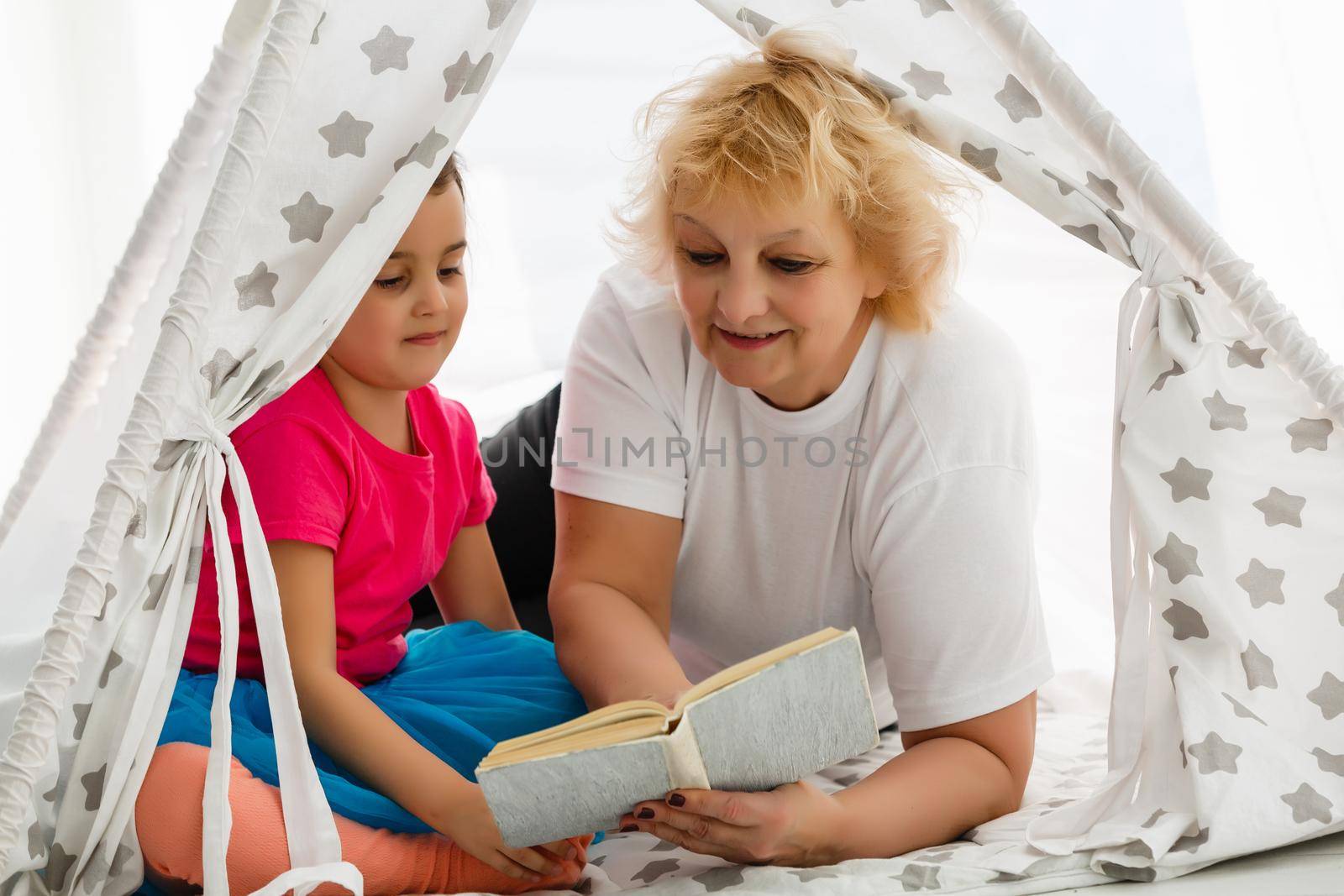 great grandmother and great granddaughter reading a book together by Andelov13