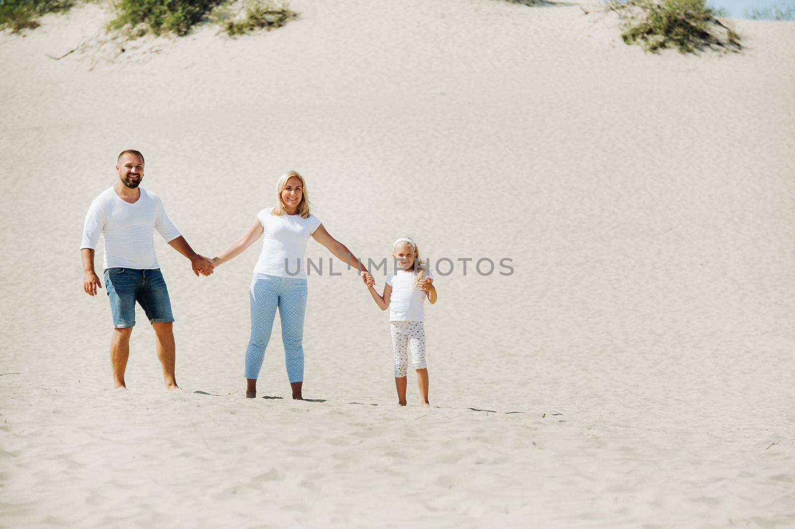 A happy family of three on the sand dunes of the Baltic sea near the city of Nida.Family trip to Europe.Lithuania.