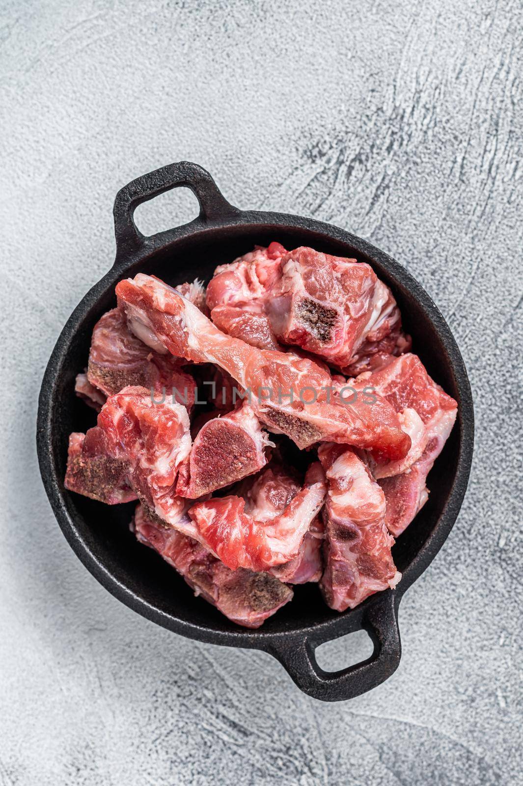 Raw diced meat cubes with bone in a pan. White background. Top View by Composter