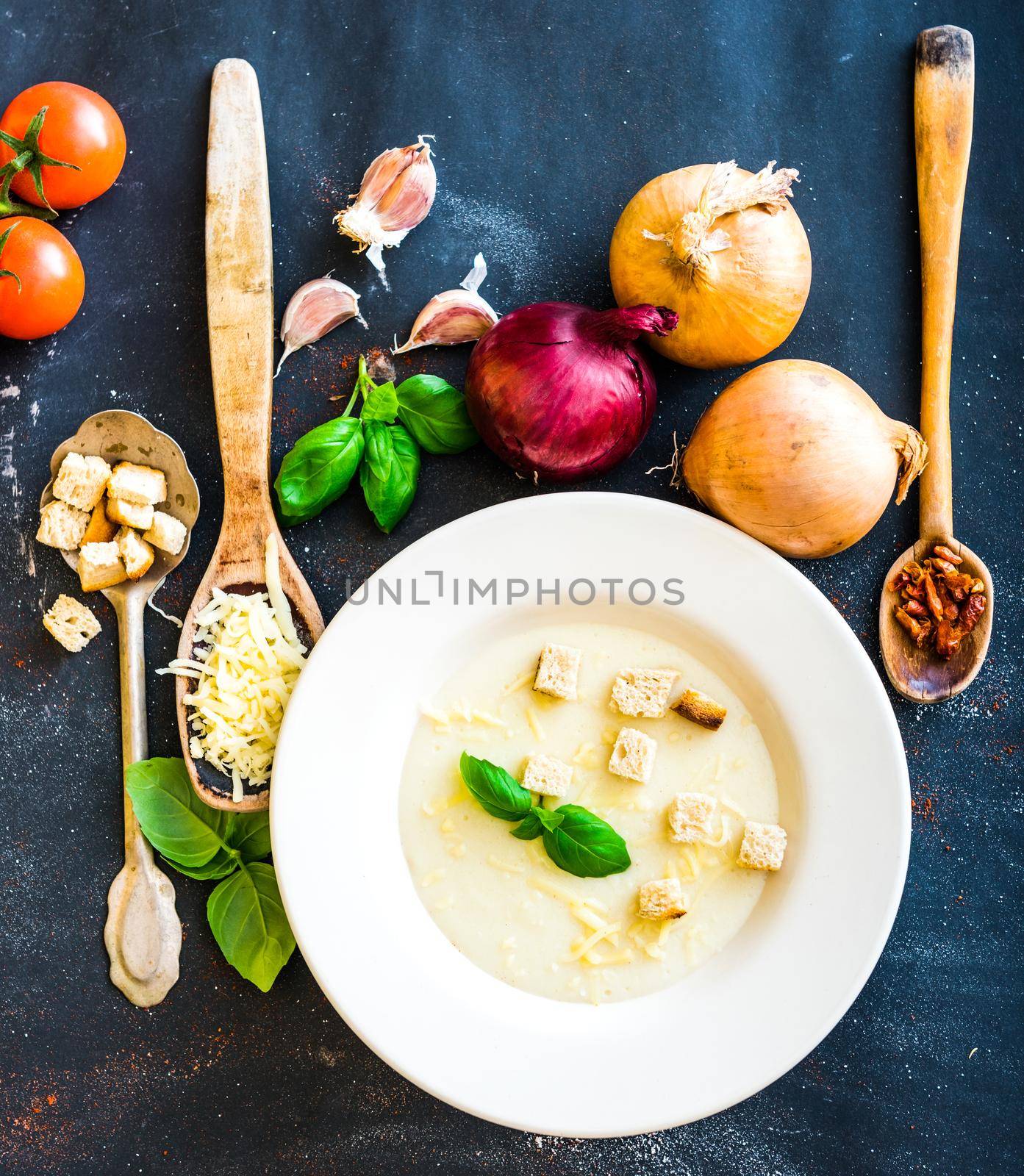 onion soup puree in a white plate with vegetables on the black background