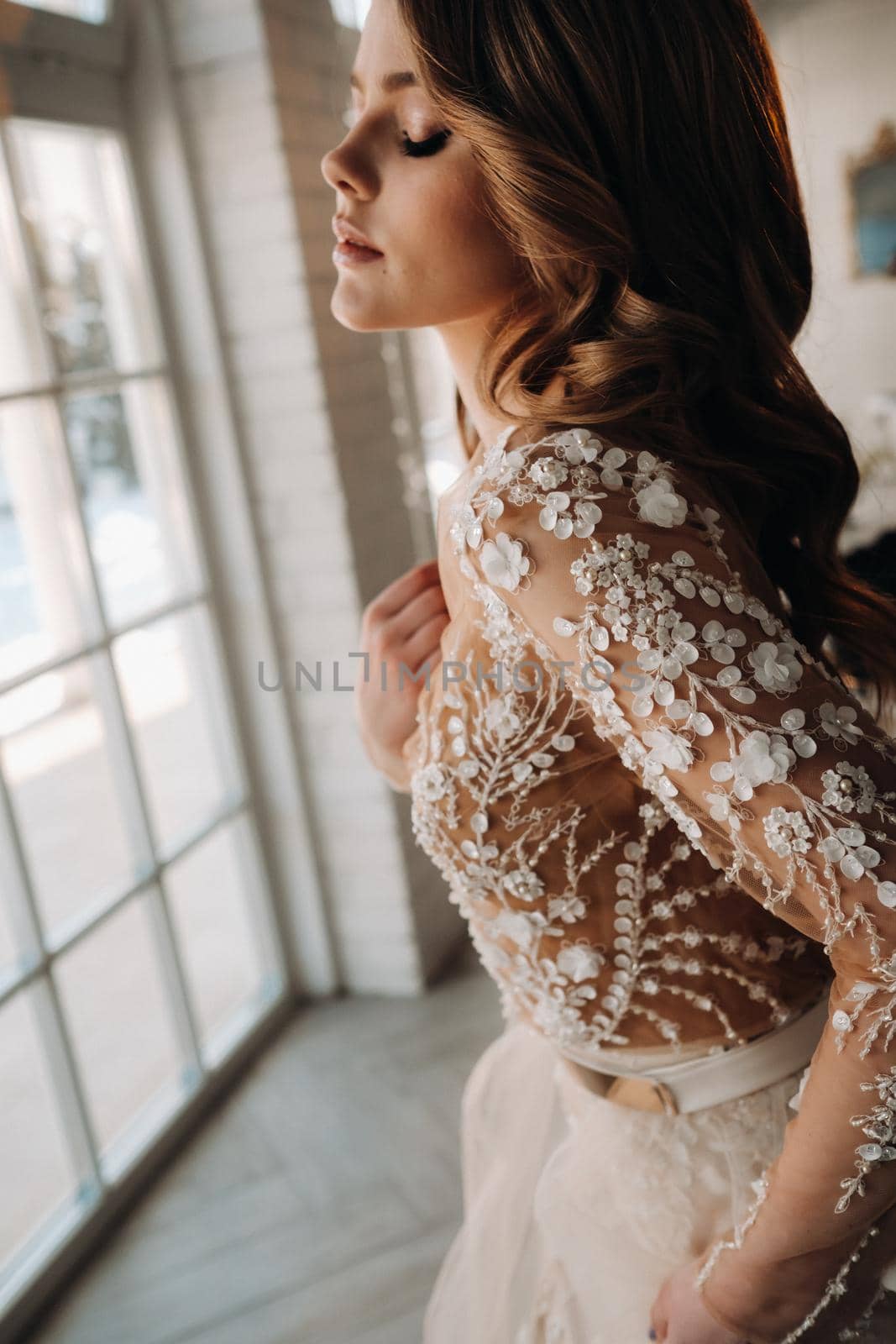 A luxurious bride in a wedding dress in the morning in her interior.