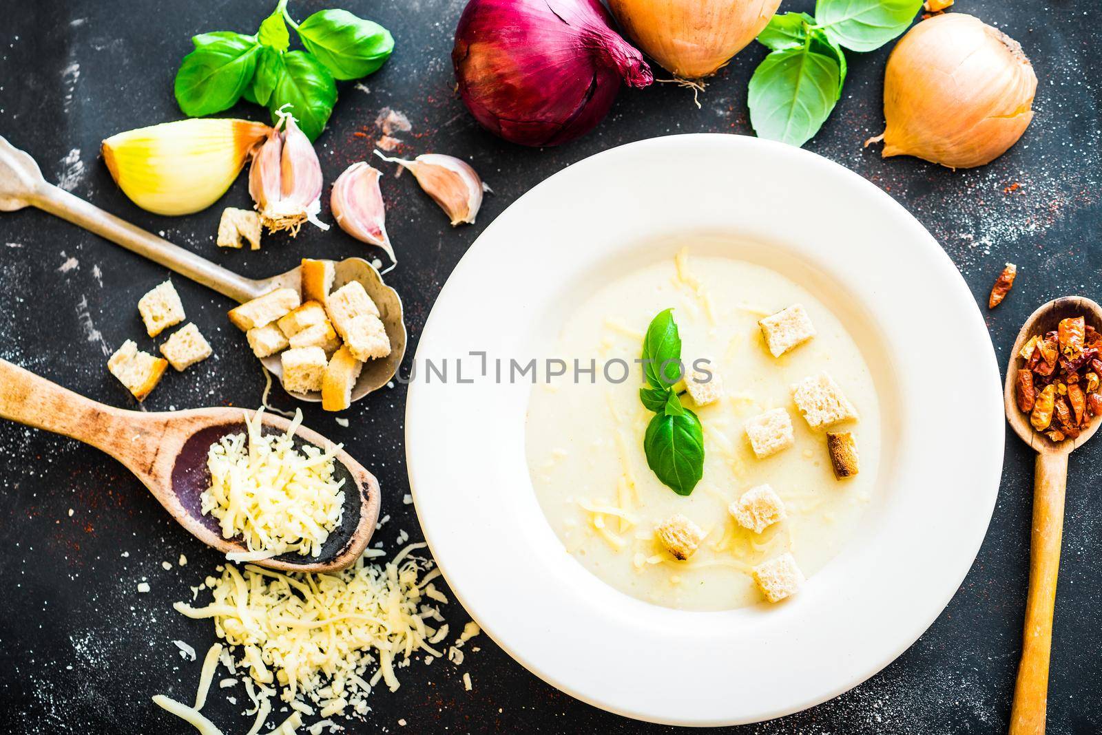 onion soup puree in a white plate with vegetables and cheese on the black table