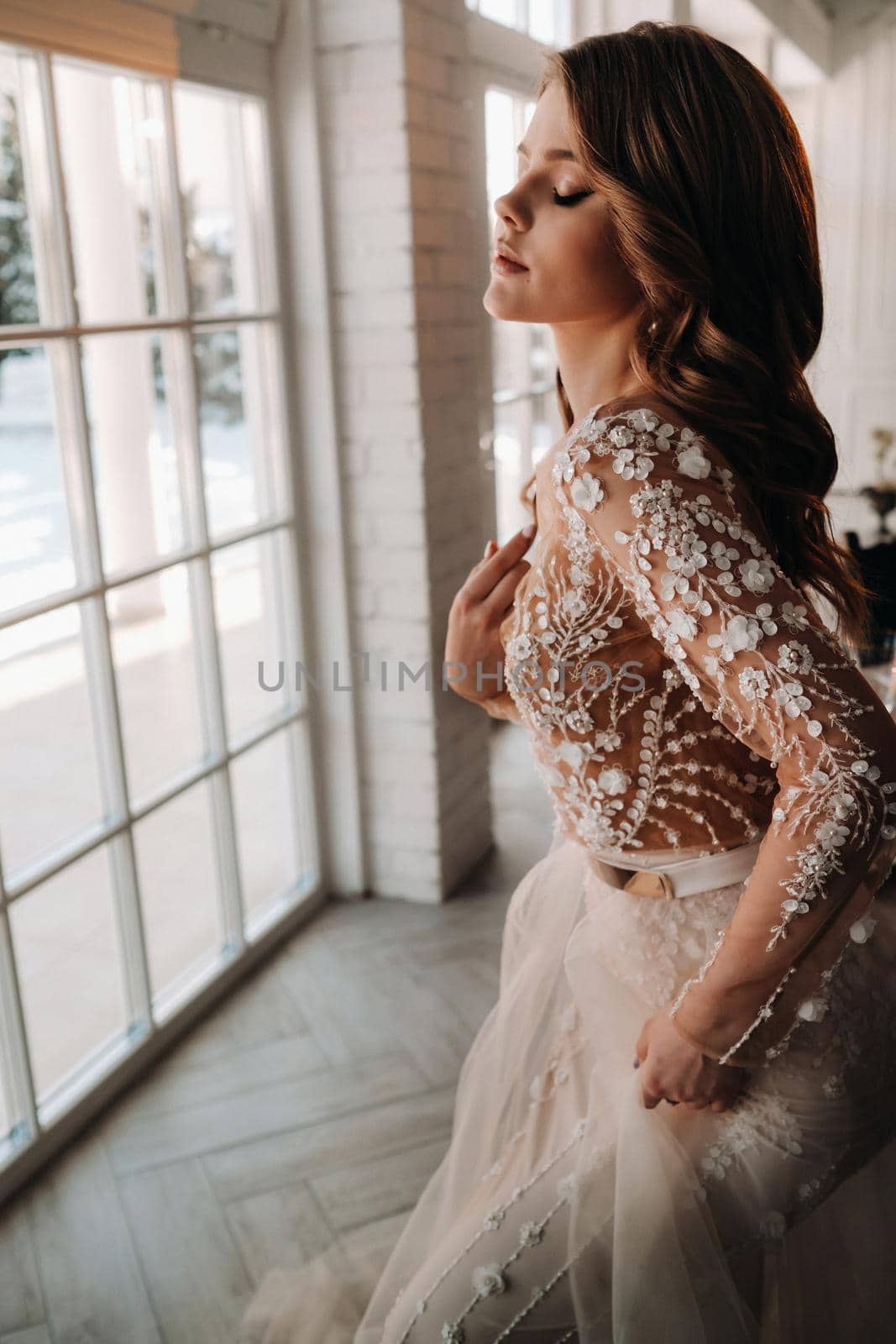 A luxurious bride in a wedding dress in the morning in her interior.