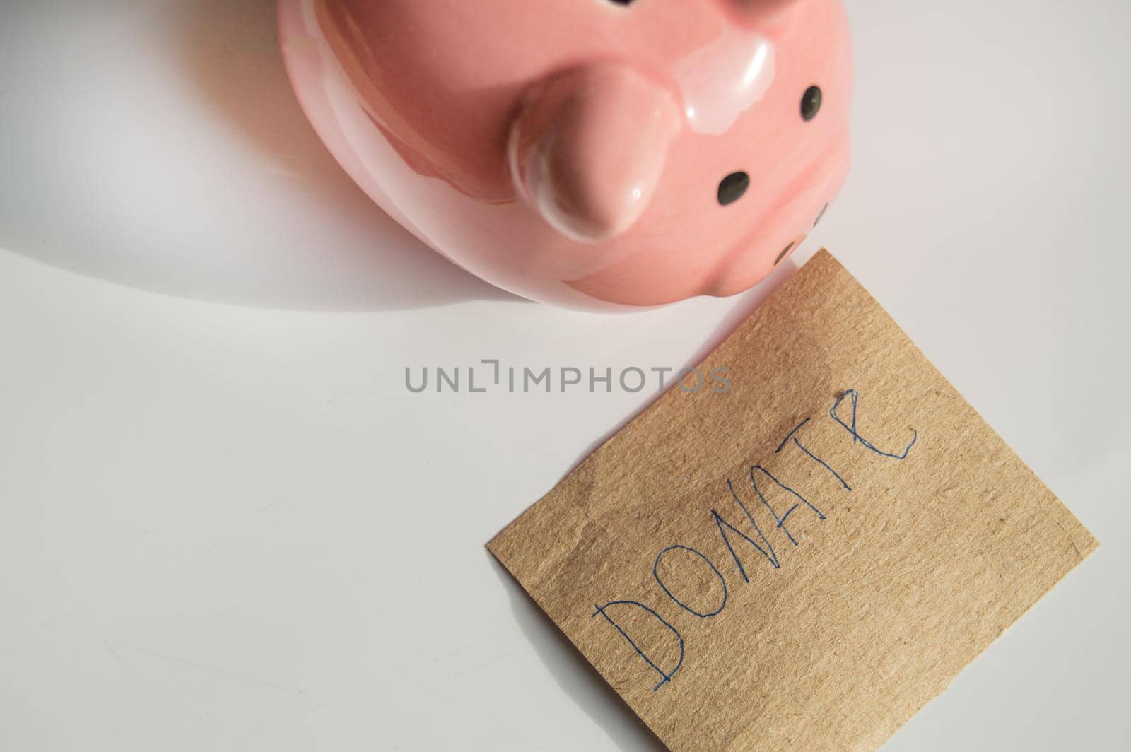 Cute pink piggy bank on a white background and a mock-up of wrapping paper with the inscription DONATE by claire_lucia