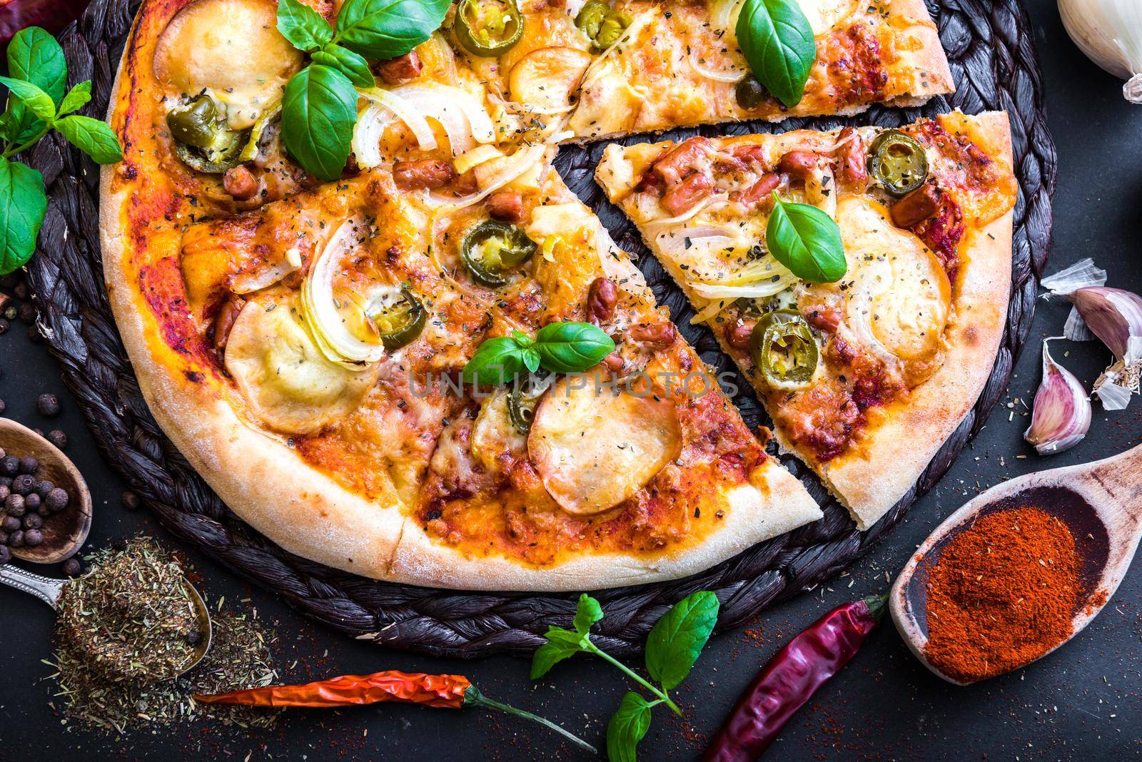 tasty pizza on a black background with spices and herbs