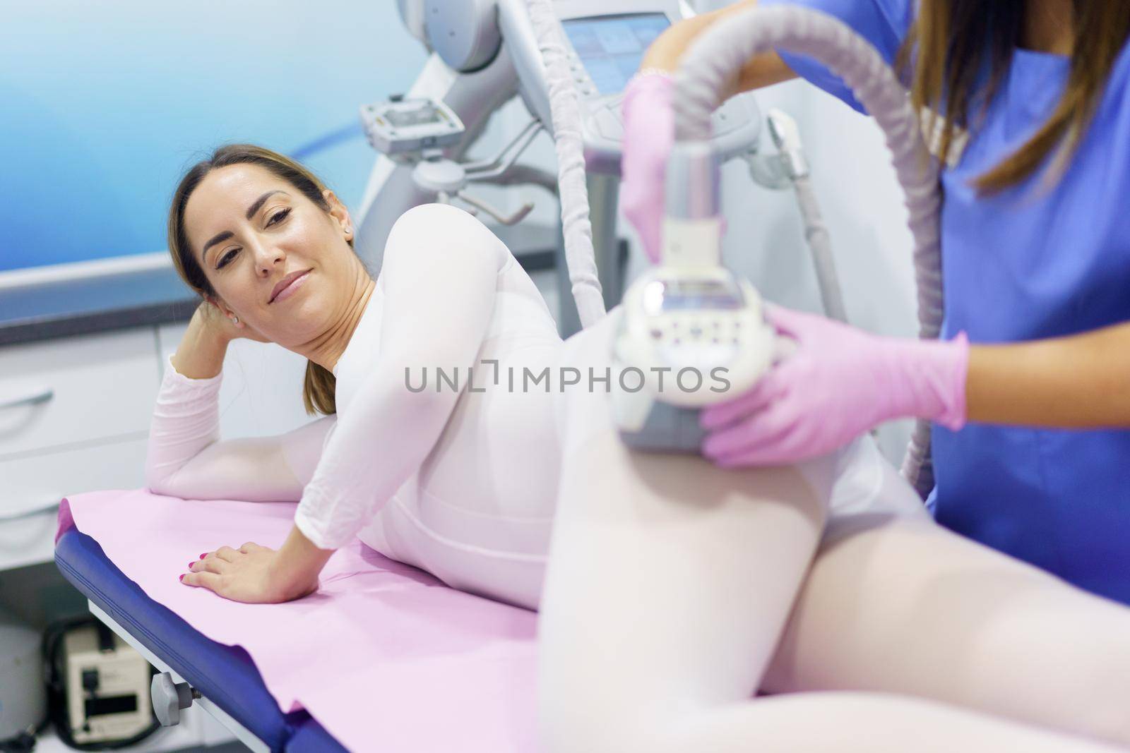Middle-aged woman in special white suit having a anti cellulite massage with spa apparatus