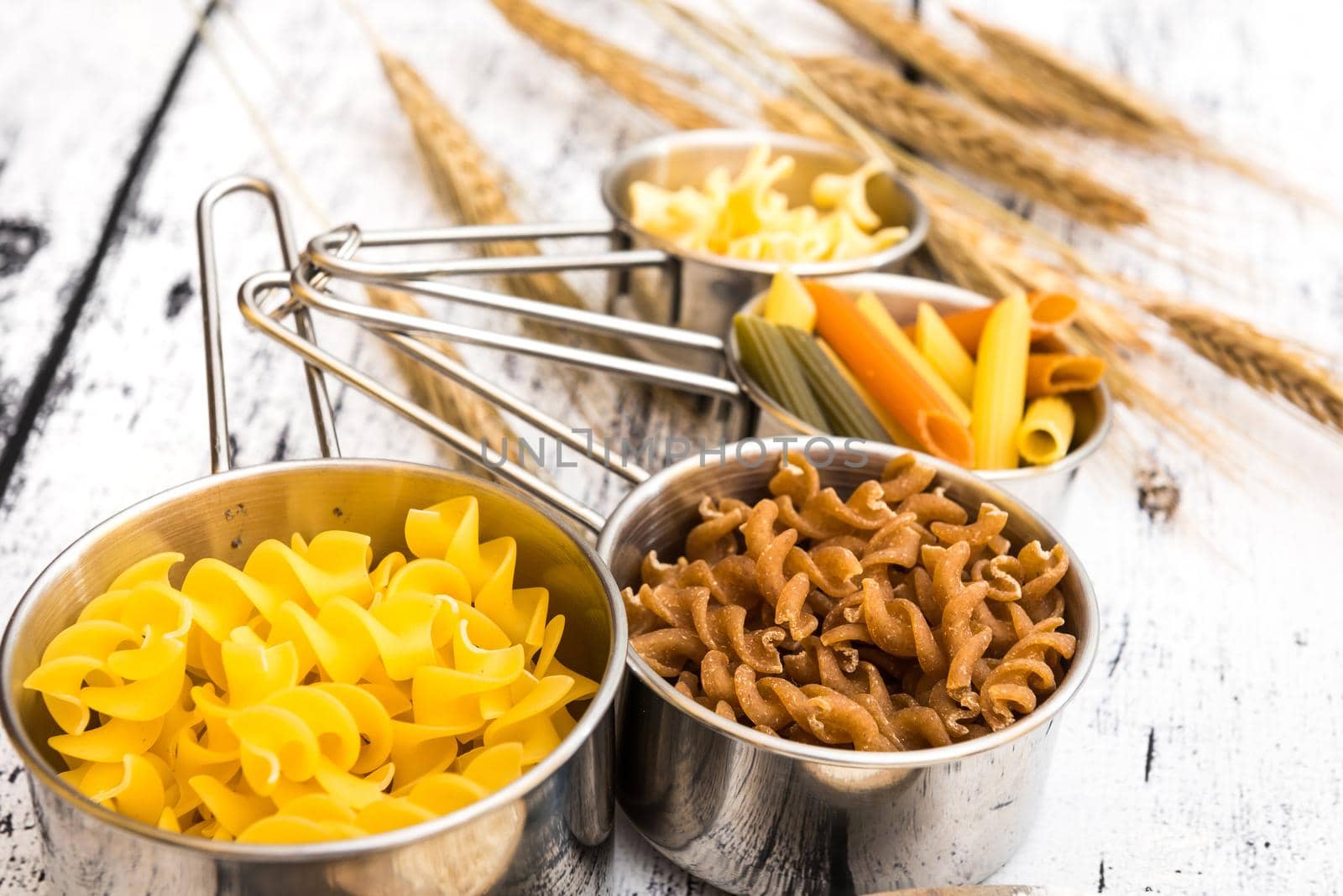 different kinds ofdifferent kinds of pasta on textured wooden table