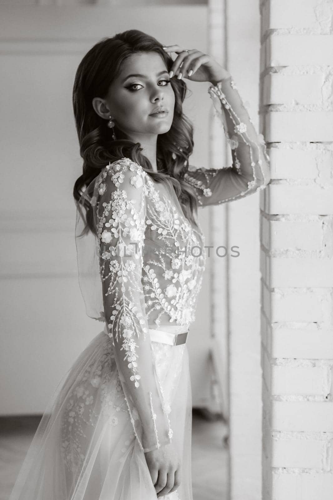 A luxurious bride in a wedding dress in the morning in her interior.Black and white photo.