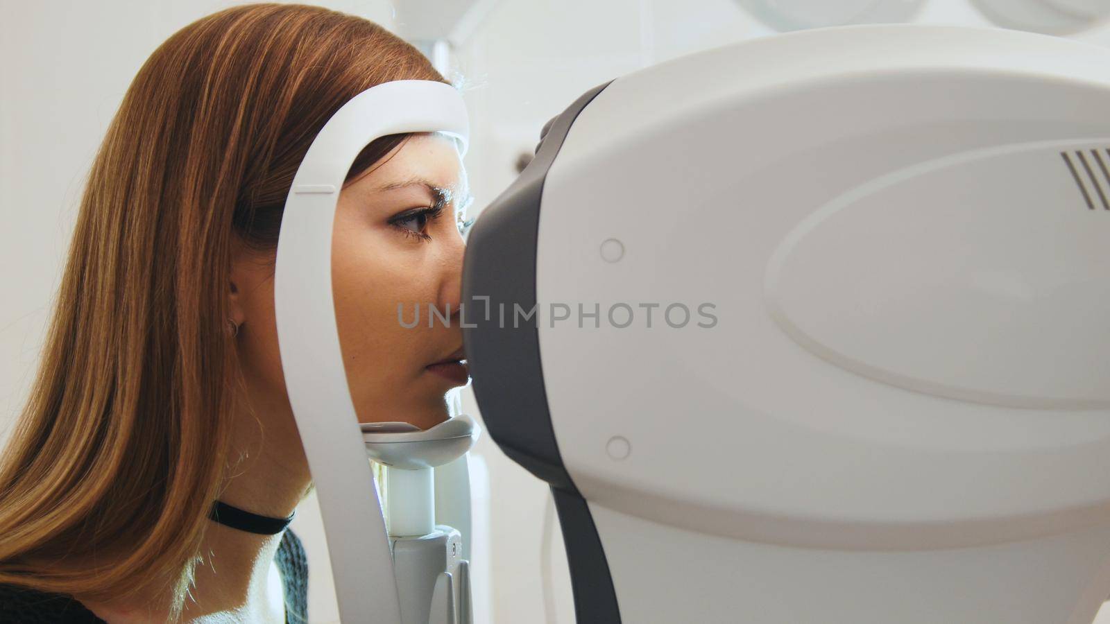 Ophthalmology clinic concept - young attractive female doing checking vision by modern electronic technology, close up