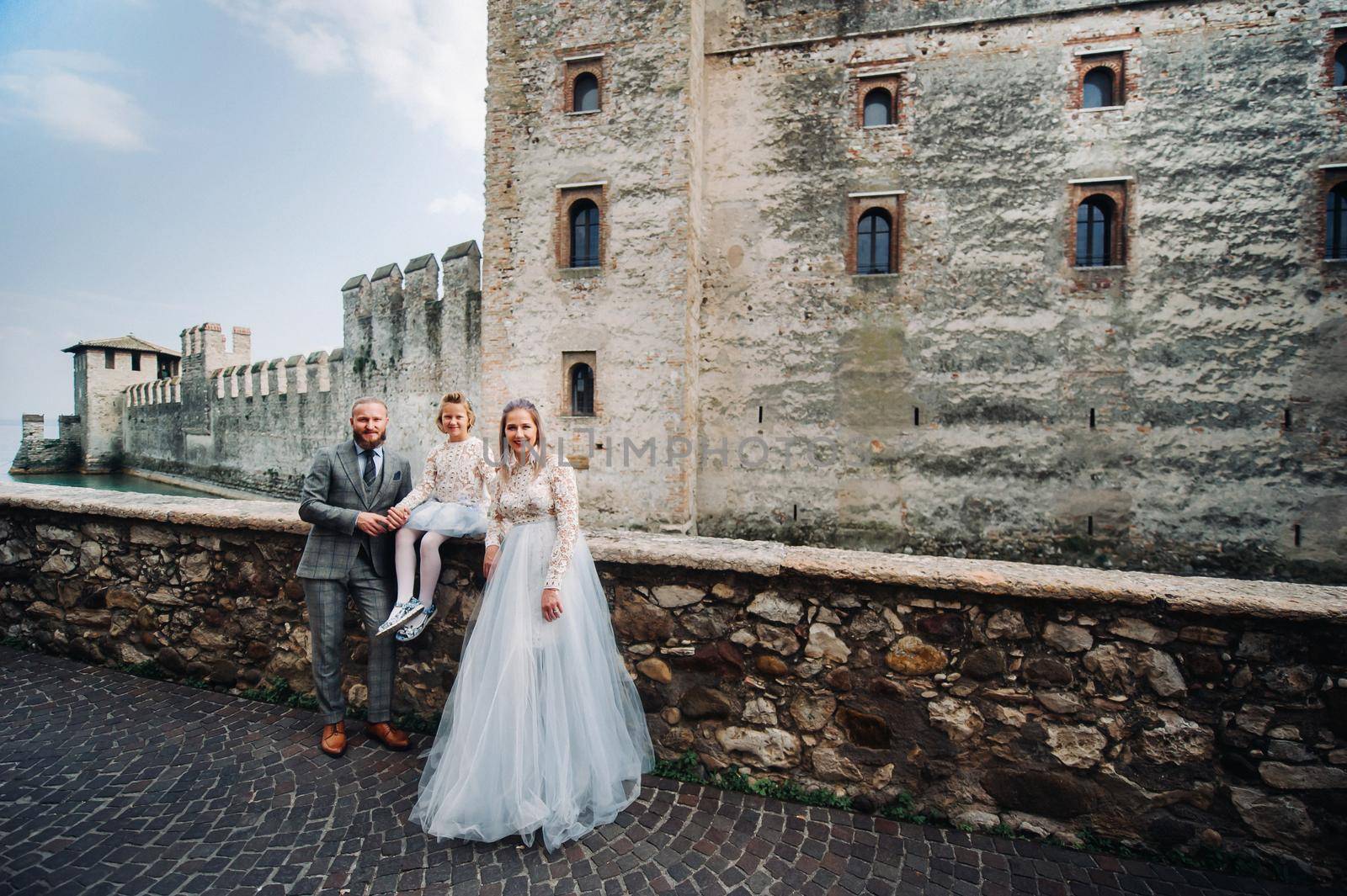 A happy young family walks through the old town of Sirmione in Italy.Stylish family in Italy on a walk by Lobachad