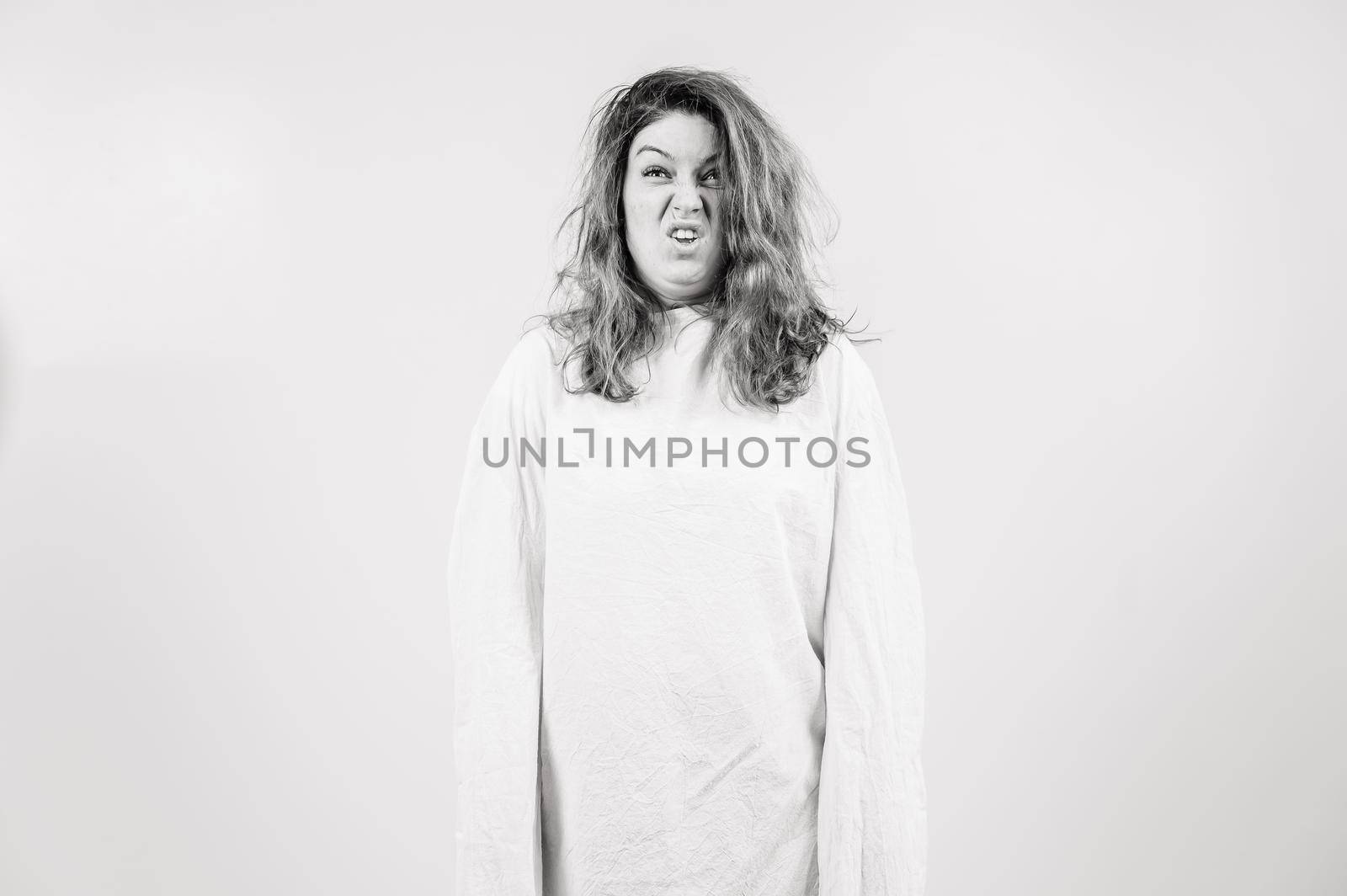 Close-up portrait of insane woman in straitjacket on white background. Monochrome