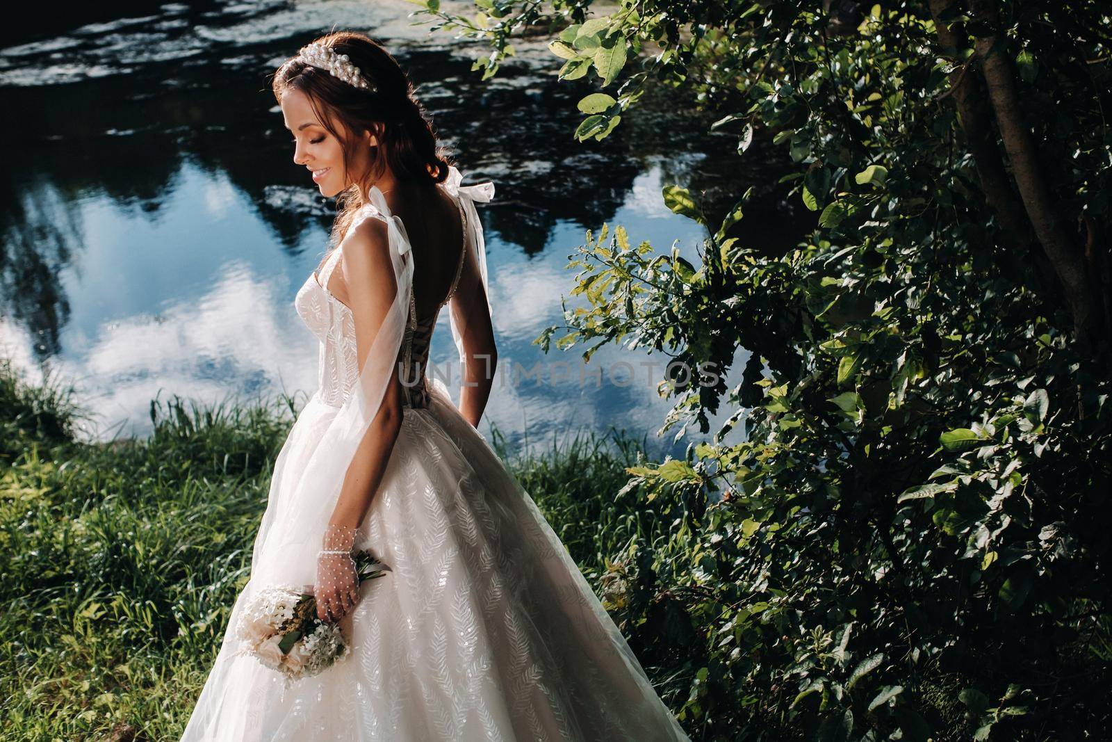 portrait of an elegant bride in a white dress with a bouquet in nature in a nature Park.Model in a wedding dress and gloves and with a bouquet .Belarus by Lobachad