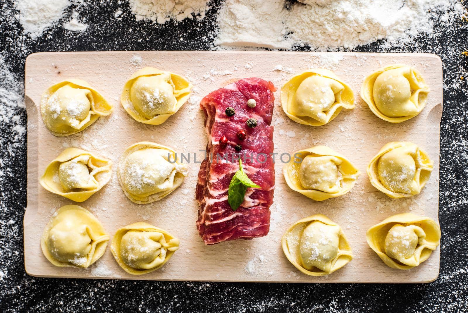 raw ravioli and different products on the black kitchen table