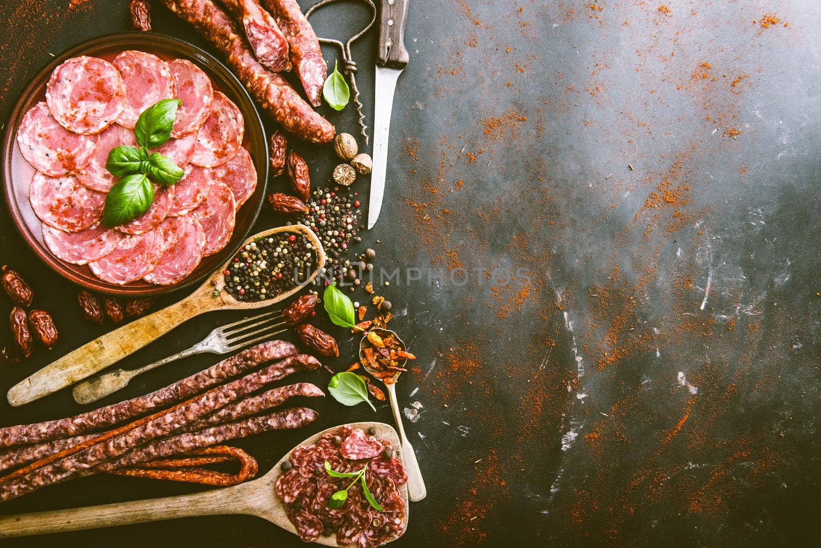 various sausages with spices on black table