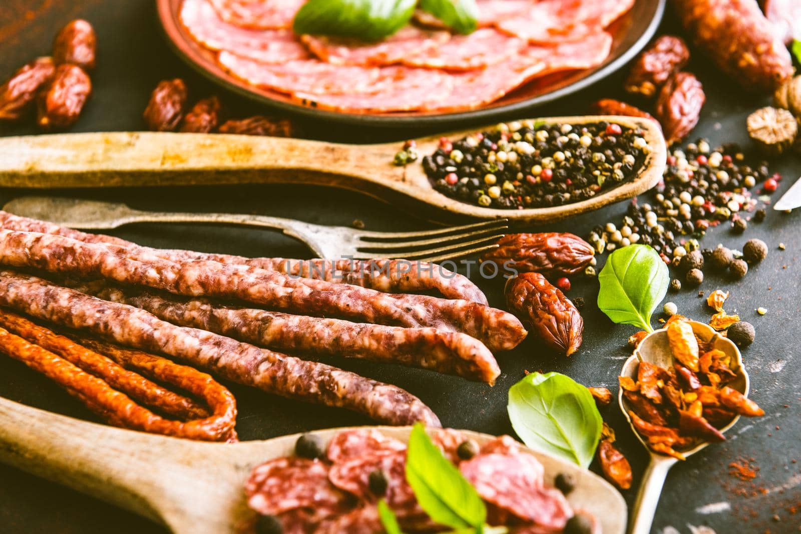 various sausages with spices on black table