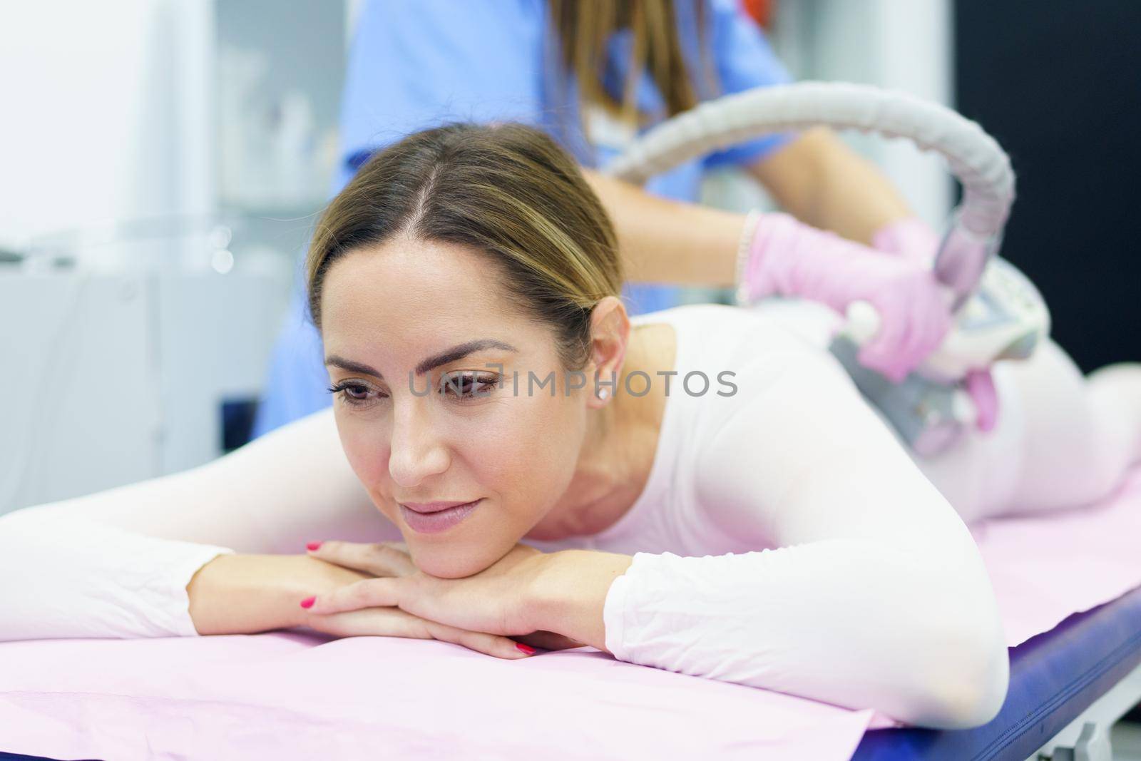 Middle-aged woman in special white suit having a anti cellulite massage with spa apparatus