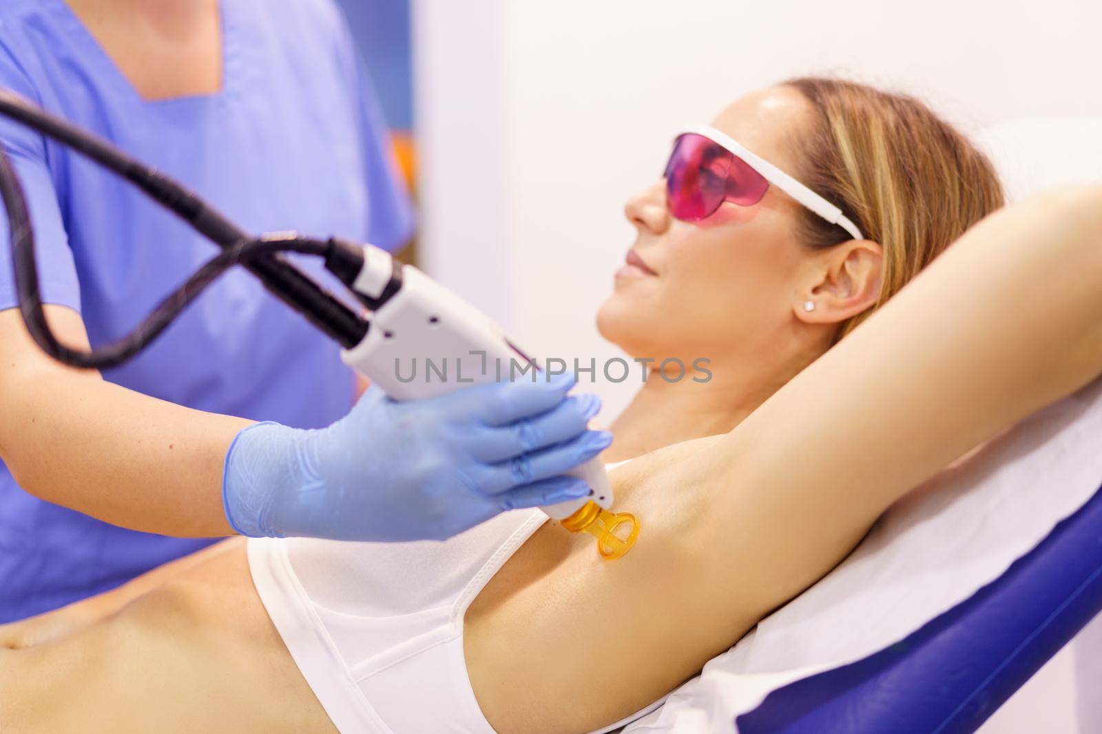 Woman receiving underarm laser hair removal at a beauty center. Laser depilation treatment in an aesthetic clinic.