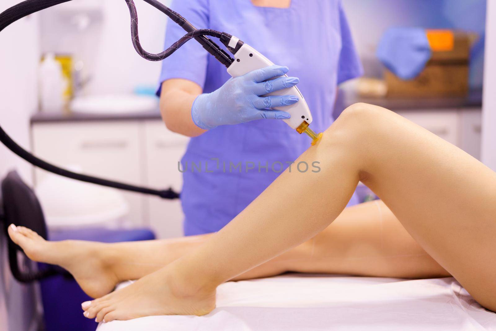 Woman receiving legs laser hair removal at a beauty center. Laser depilation treatment in an aesthetic clinic.