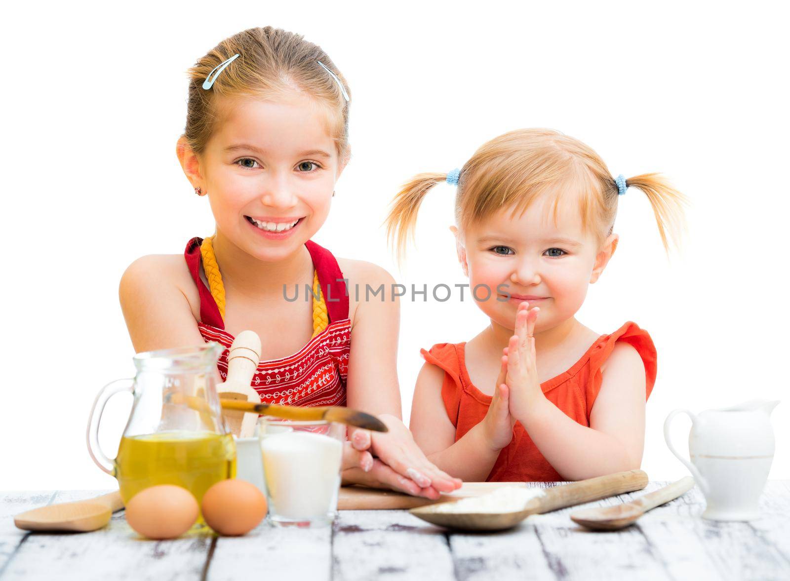 two cute little sisters cooking isolated on a white background