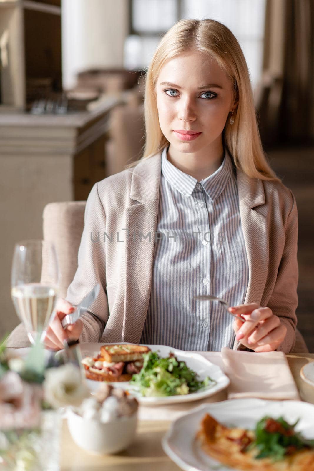 Portrait of a beautiful young elegant blonde woman in the cafe with a glass of champagne