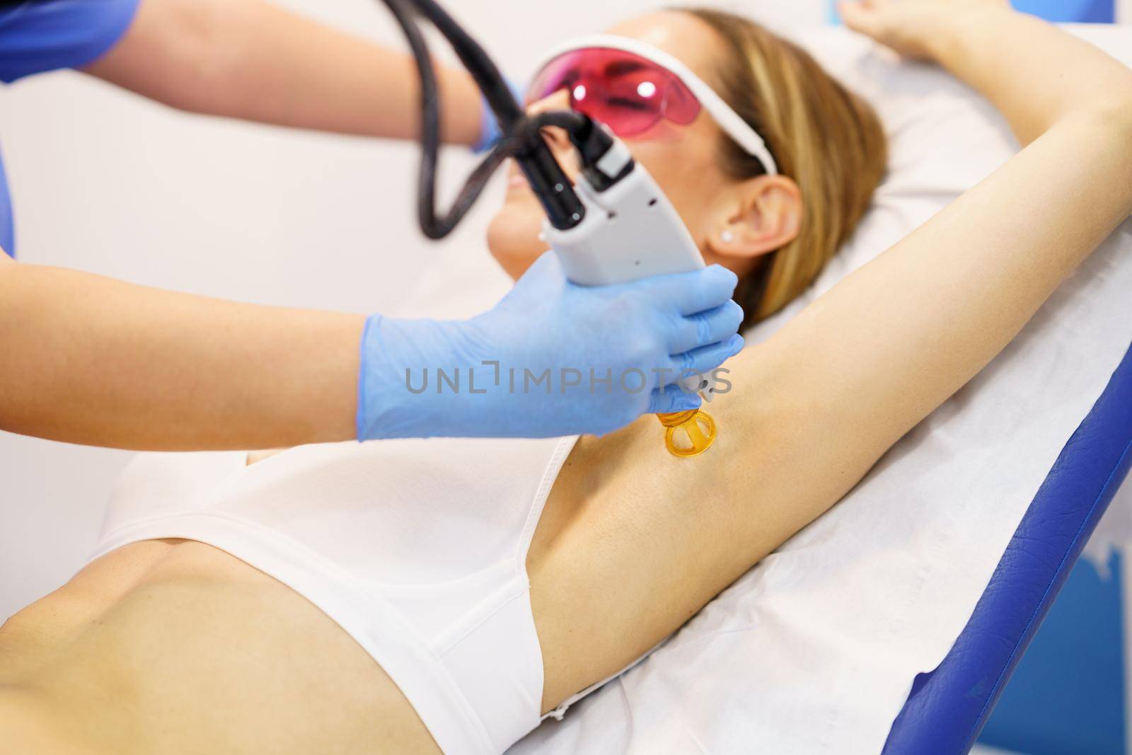 Woman receiving underarm laser hair removal at a beauty center. Laser depilation treatment in an aesthetic clinic.