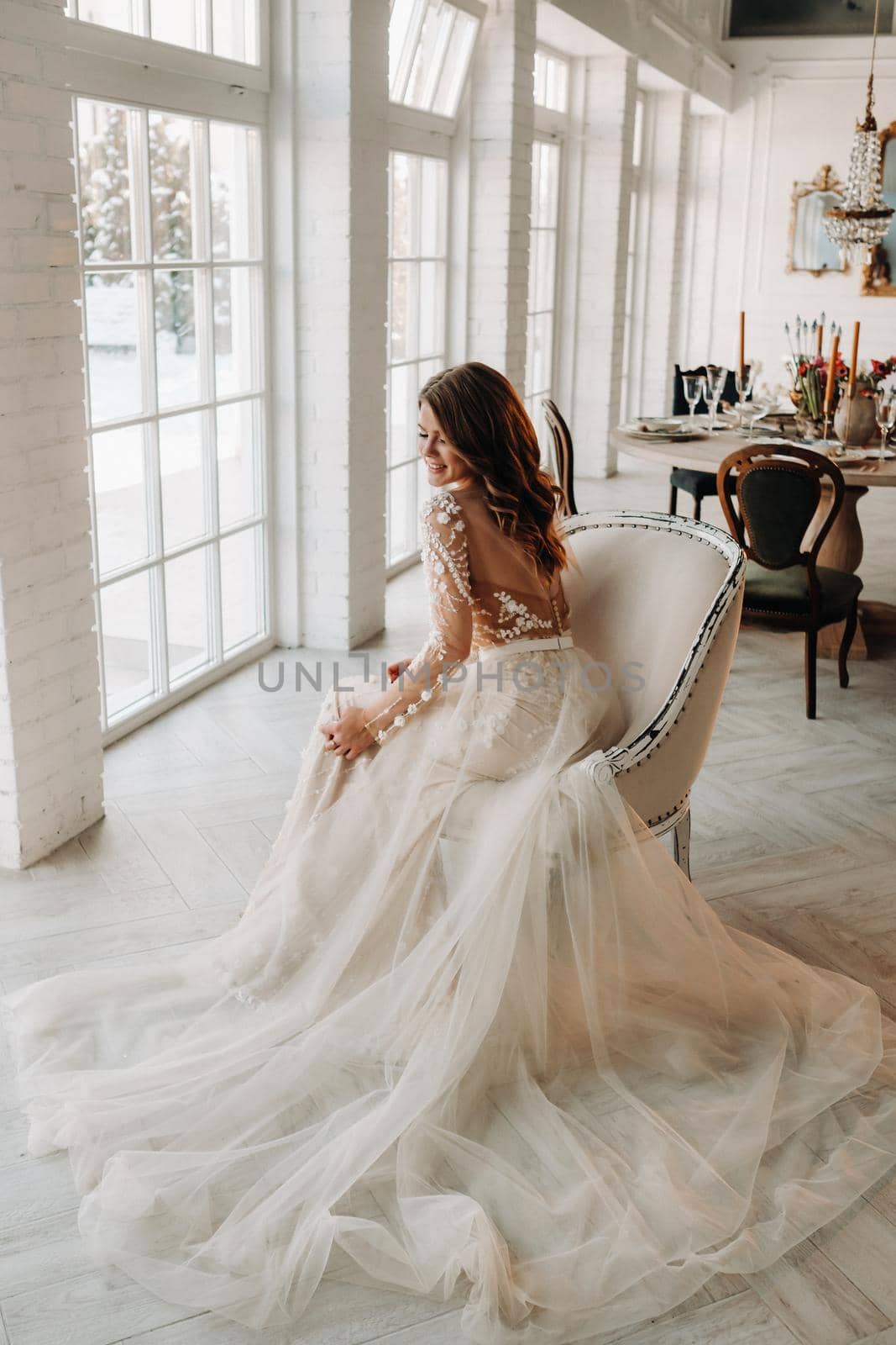 A luxurious bride in a wedding dress in the morning in her interior.