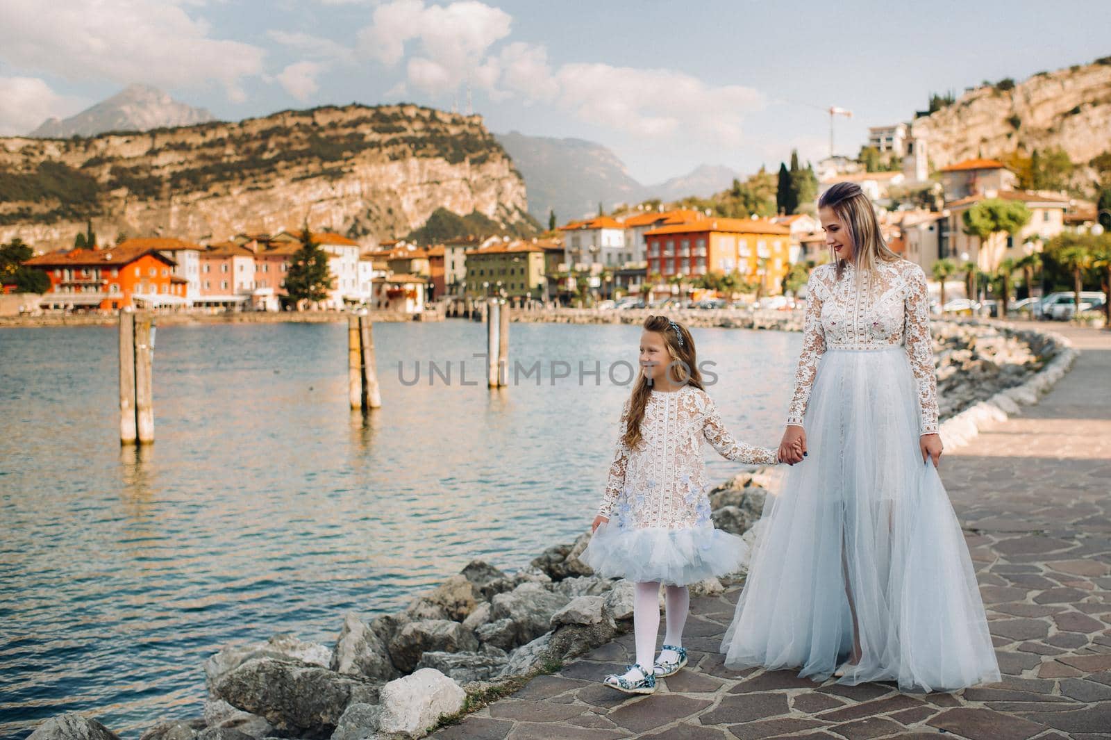 Italy, Lake Garda.Stylish Mother and daughter on the shores of lake Garda in Italy at the foot of the Alps. mother and daughter in Italy by Lobachad