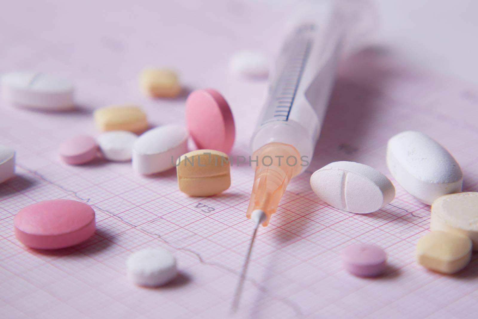 syringe and pills on blue background, close up .