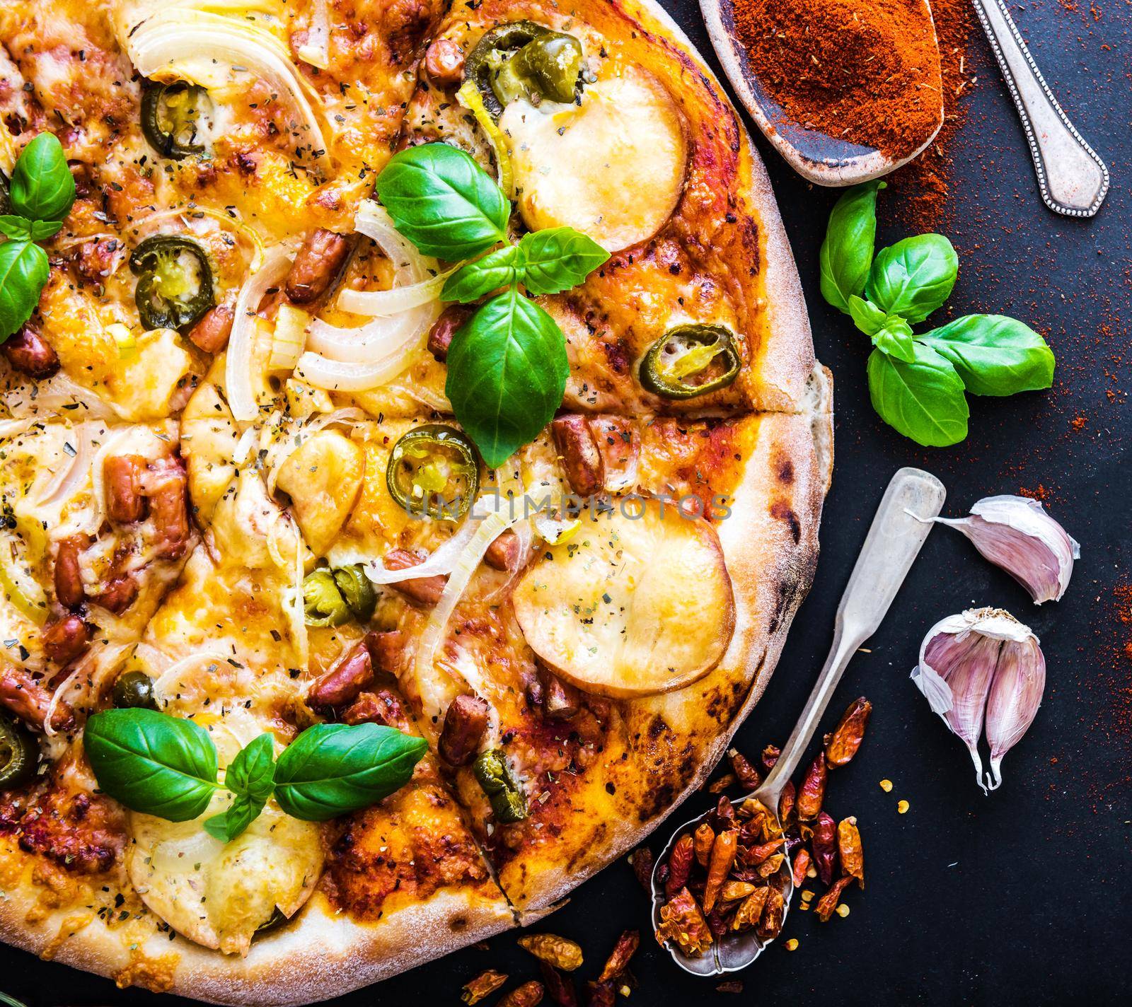 tasty pizza on a black background with spices and vegetables