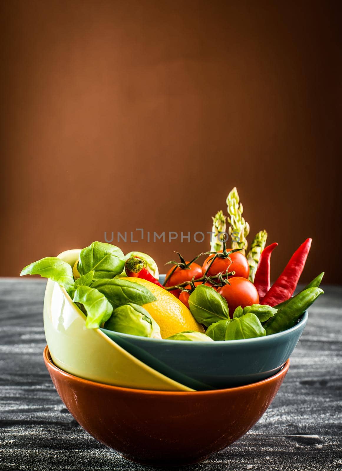 Fresh vegetables in a bowl on the table with brown background