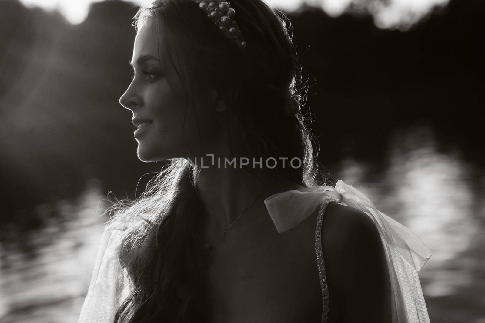 An elegant bride in a white dress enjoys nature at sunset.Model in a wedding dress in nature in the Park.Belarus. black and white photo by Lobachad