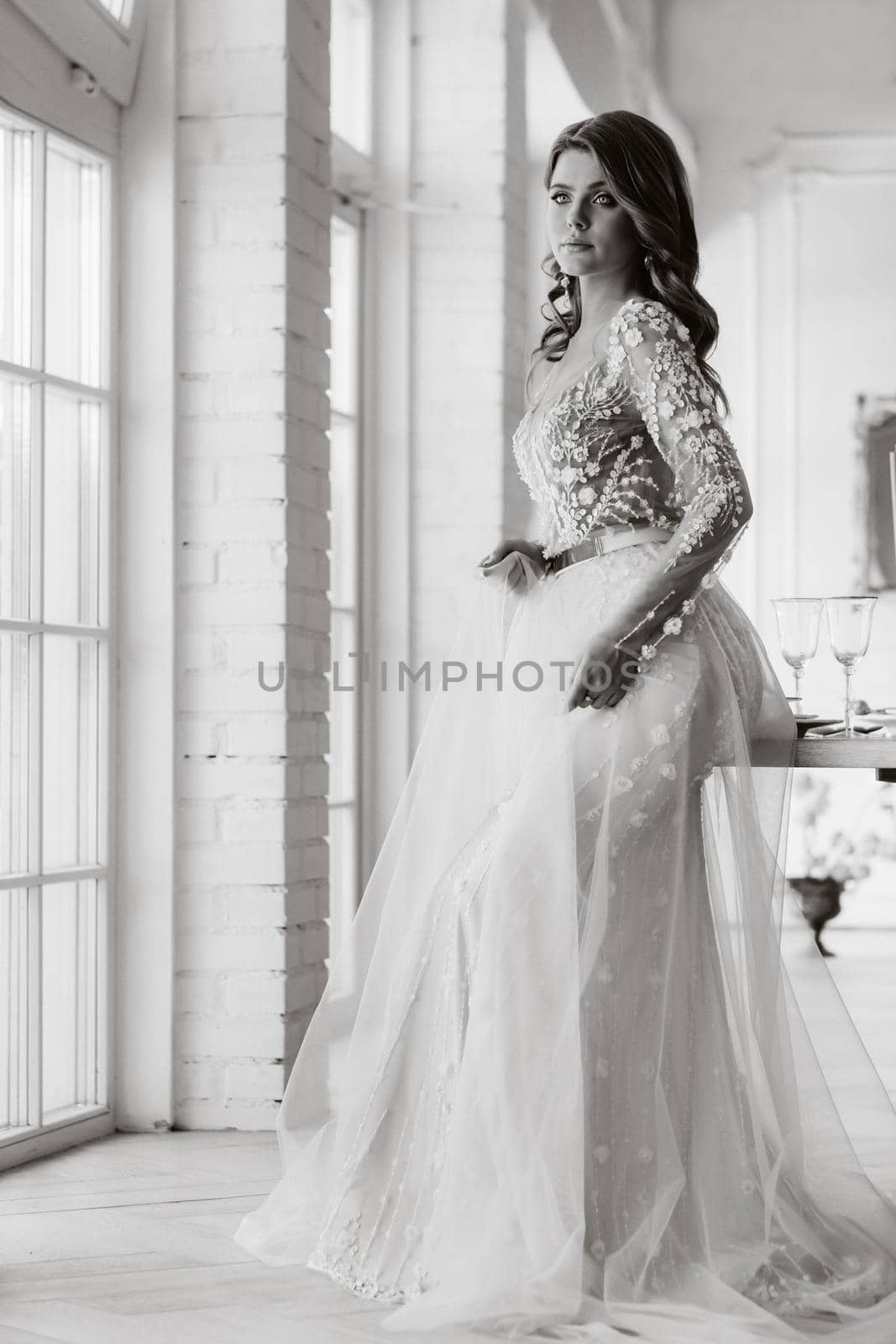 A luxurious bride in a wedding dress in the morning in her interior.Black and white photo by Lobachad