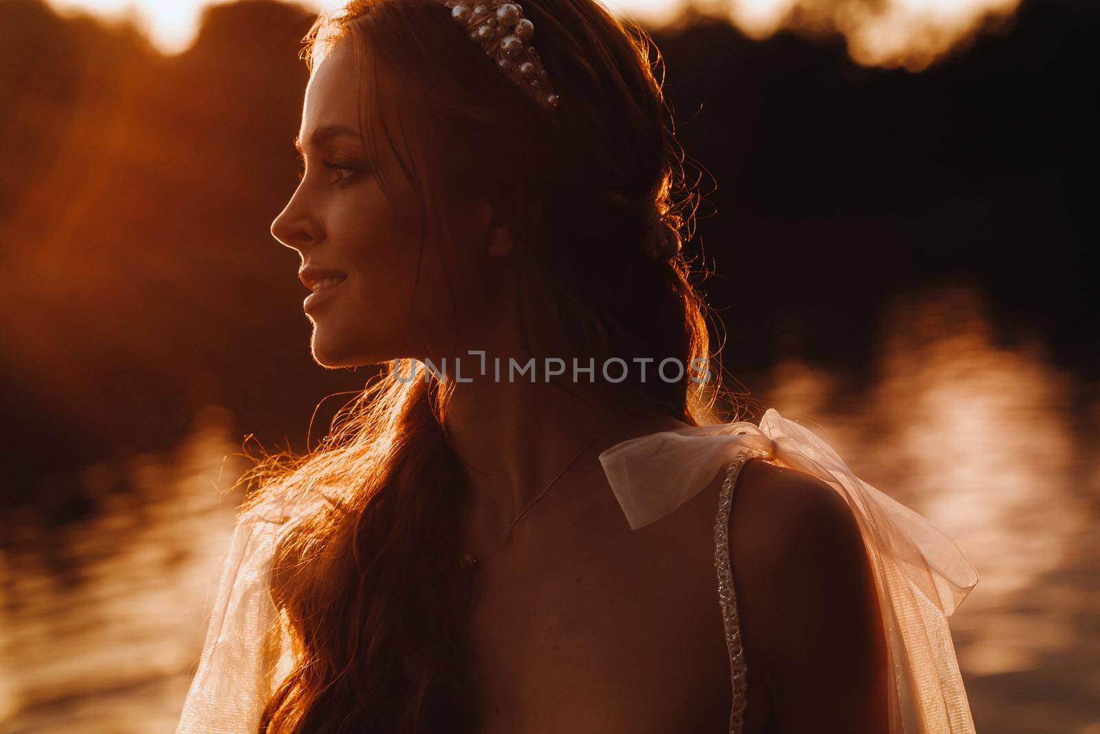 An elegant bride in a white dress enjoys nature at sunset.Model in a wedding dress in nature in the Park.Belarus.