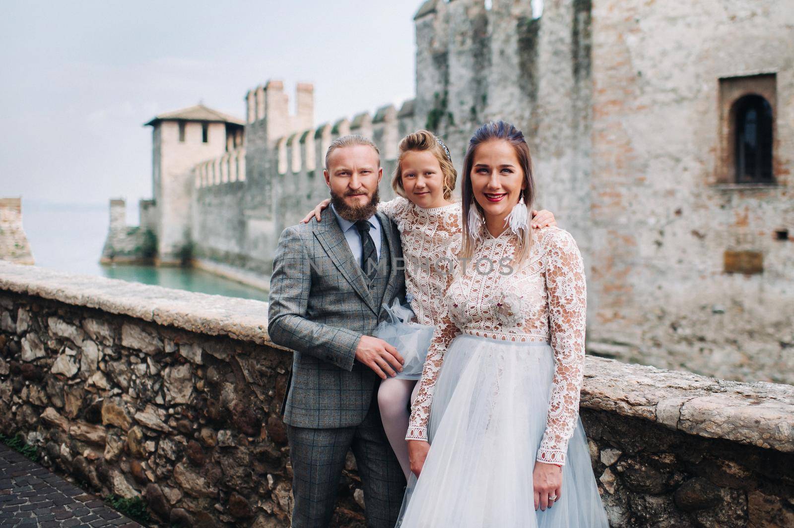 A happy young family walks through the old town of Sirmione in Italy.Stylish family in Italy on a walk by Lobachad