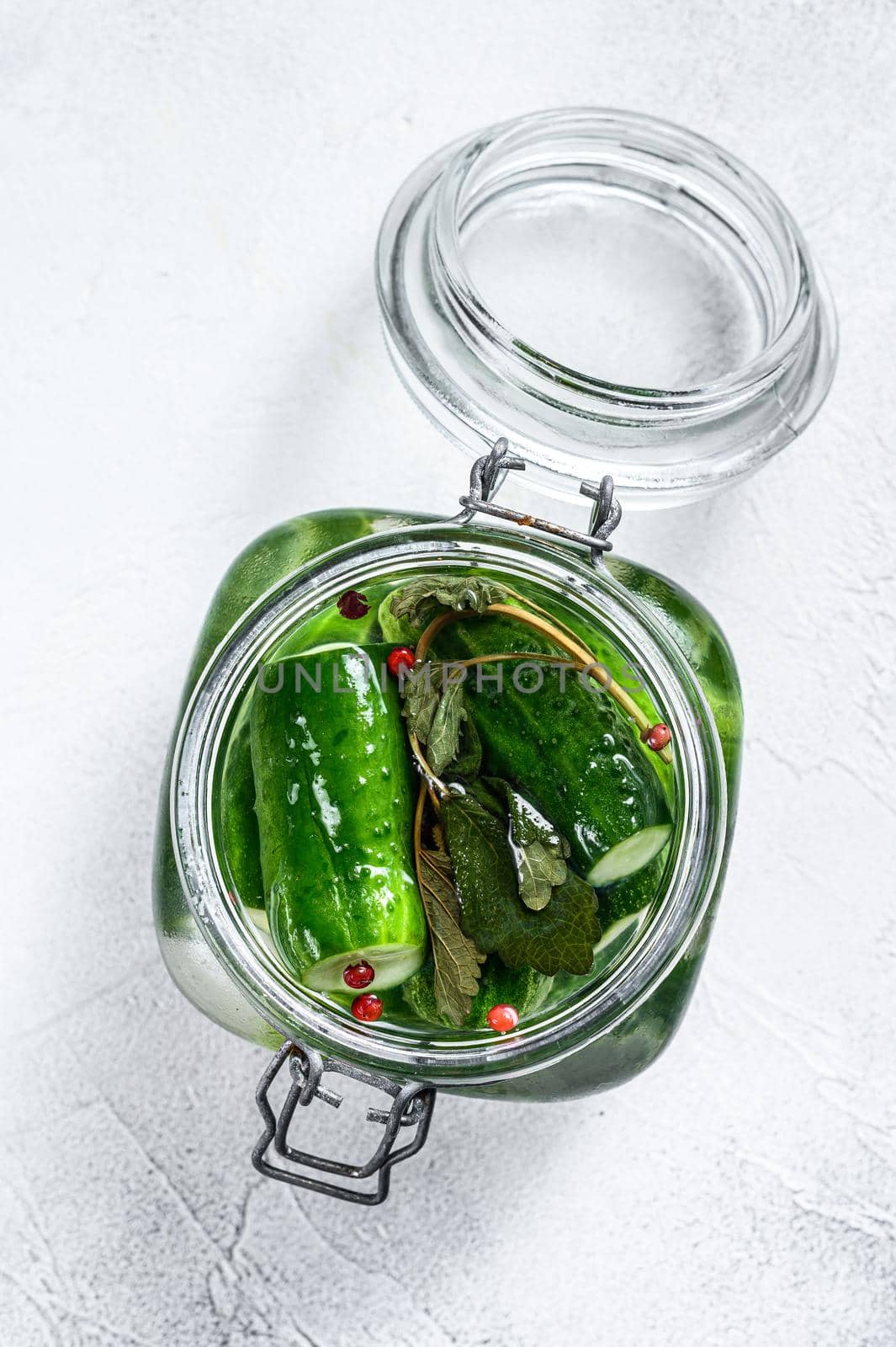 Green pickle cucumbers in a glass jar. Natural product. White background. Top view by Composter