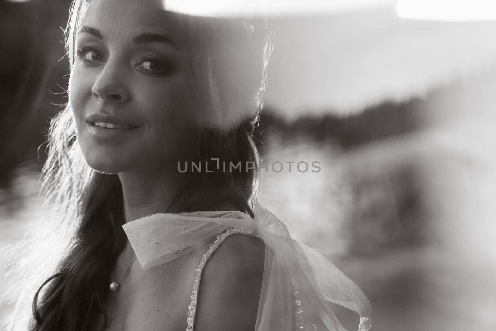 An elegant bride in a white dress enjoys nature at sunset.Model in a wedding dress in nature in the Park.Belarus.black and white photo.